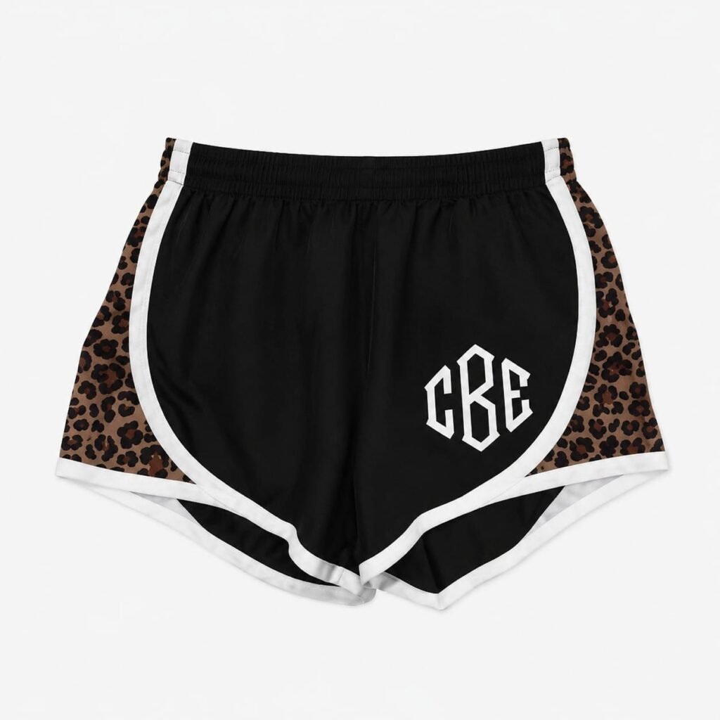 Black custom athletic shorts with white trim, leopard-print side panels, elastic waistband, and CBE logo.